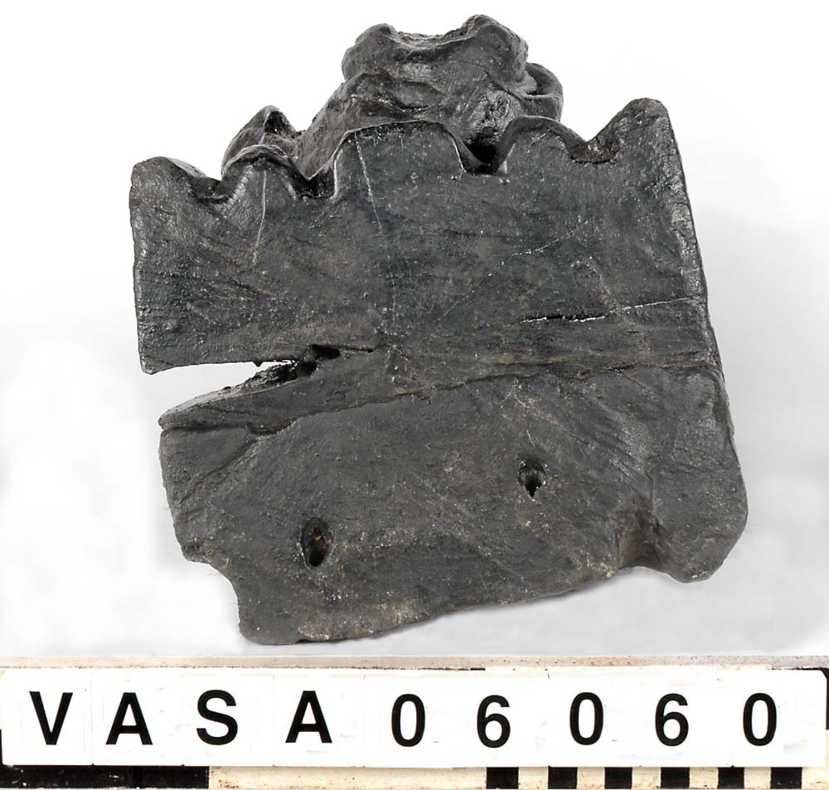 Skulptur föreställande en barnfigur som spelar på en sinka (ett äldre blåsinstrument med grepphål som blockflöjten men ett munstycke som liknar trumpetens).
Huvudet är vridet något åt höger. Kroppstyngden vilar på höger ben medan vänster ben är böjt. Instrumentet hålls med båda händerna. Skulpturen förefaller delvis draperad i en mantel eller dylikt som skymtar vid hans högra sida. Ovanför hjässan syns en något snedställd äggstavslist. Figuren står på ett minimalt underlag som troligen avser att föreställa ett stycke naturlig mark. Skulpturens baksidan är slät.
Skulpturen är kraftigt sliten.

Text in English: A sculpture of a child playing a sinka.
The weight of the body rests on the right leg while the left is bent and the head is turned slightly to the right.. The instrument is held in both hands. The figure seems to be partly draped in a cloak or the like, which conceals his right side. Just above the head the back board comes forward at right angles and the front of the board is decorated with an egg  mould design. The sculpture stands on a small flat plinth. The back of the sculpture is smooth.
The sculpture is very worn.