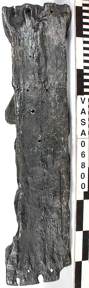 Skulptur föreställande en barnfigur spelande på en viola da braccio.
Fiolen hålles med vänster hand och stöder mot vänster knä. Kroppstyngden vilar på höger ben. Huvudet är vridet åt höger. Antydan till mantel utmed höger sida. Ovanför hjässan ses en äggstavslist. Figuren står på ett minimalt underlag som troligen avser att föreställa ett stycke naturlig mark. Skulpturens baksida är slät
Skulpturen är kraftigt sliten. Höger underarm är bortbruten.

Text in English: This is a sculpture of a child holding a viola da braccio in the left hand and supported on the left knee.
The weight of the body rests on the right leg. The head is turned to the right. There is the suggestion of a mantle on the figures right side. Just above the head, the back board comes forward at right angles and the front of the board is decorated with an egg moulding design. The figure stands upon a small plinth. The back of the sculpture is smooth.
The sculpture is very worn and the right forearm is broken off.