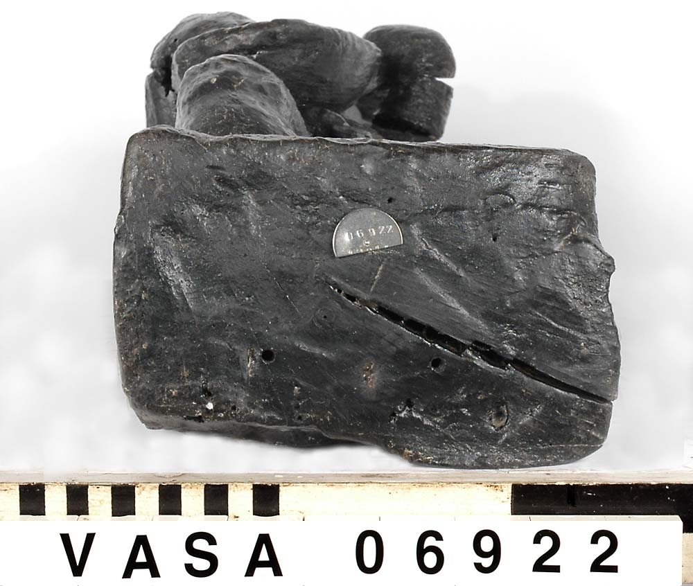 Skulptur föreställande en barnfigur med en cister (ett stränginstrument som tillhör familjen lutor).

Instrumentet hålls med bägge händer framför kroppen. Huvudet något vridet åt vänster. Kroppstyngden vilar på vänster ben medan höger ben är böjt. Utmed höger sida skymtar en mantel. Figuren står på ett minimalt underlag som troligen avser att föreställa ett stycke naturlig mark. Skulpturens baksida är slät.

Skulpturen är välbevarad.



Text in English: This is a sculpture of a child playing a cister.

It holds the instrument in both hands in front of its body. The head is turned slightly to the left. The weight of the body rests on the left leg, the right leg is bent. A mantle or cloak is to be seen on the figures right side. The child stands upon a small flat plinth. The back of the sculpture is smooth.

The sculpture is well preserved.