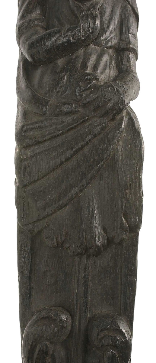 Hermpilaster.
Liten skulpterad pilaster föreställande skäggig herm under joniskt kapitäl.
Huvudet är vridet mot vänster. Hermen är insvept i en mantel som hålls fast med vänster hand framför magen. I höger hand håller figuren ett okänt föremål (blomsterkälk?) framför bröstet. Pilasterskaftet är prytt med stora frukter och blad, fasthängande vid en stängel som delvis täcker det nedåt avsmalnande skaftets ramverk. Baksidan är slät.
Skulpturen är mycket välbevarad med sju spikhål.

Text in English: Small sculpted pilaster with a bearded Herm beneath an Ionic capital.
The head of the figure is turned to the left. The Herm is enveloped in a mantle, held fast with the left hand in front of its stomach. Its right hand holds an unknown object (a bunch of flowers?) in front of its breast. The shaft of the pilaster is decked with large fruit and leaves hanging from a stalk which partly cover the framing of the tapering shaft. Its back is flat.
The sculpture is very well preserved.
