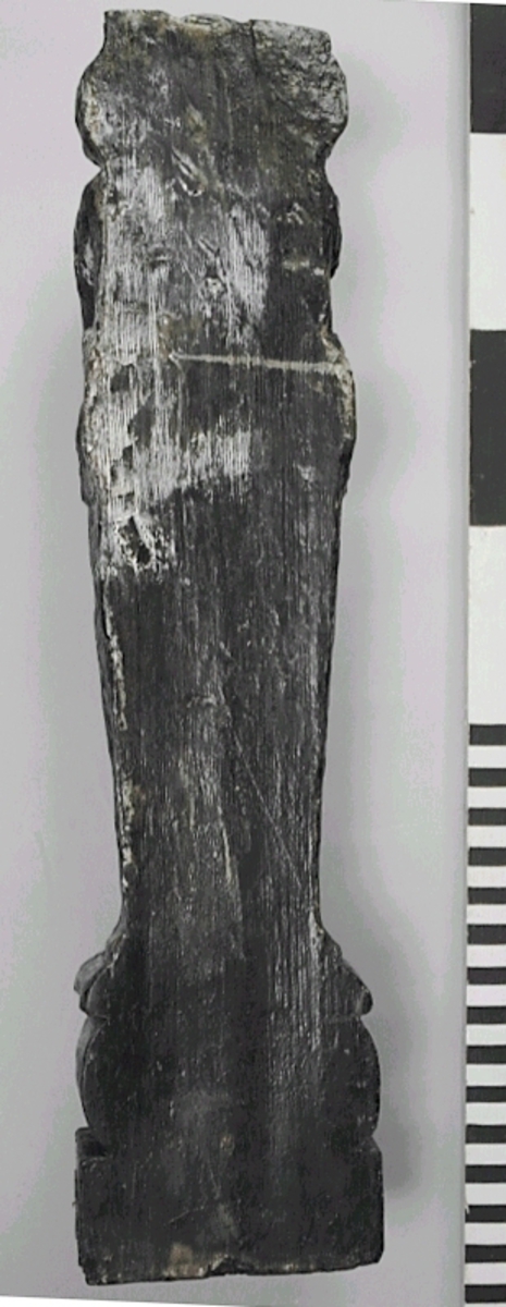 Liten skulpterad pilaster, utformad som en karyatid eller möjligen en putto. Figuren har långt hår och ett knubbigt ansikte, omgivet av en bred krage. Det nedåt avsmalnande pilasterskaftet är dekorerat med akantusblad. Nedtill avslutas pilastern av en rikt profilerad och dekorerad sockel. Skulpturens baksida är slät.
Skulpturen är sliten, främst den övre delen.

Text in English: A small carved pilaster, with a caryatid or probably a putto. The figure has a chubby face, long hair and a broad collar. The lower part of the pilaster is decorated with acanthus leaves. The caryatid stands on a richly profiled and decorated socle. The back of the sculpture is smooth.
The sculpture is worn.