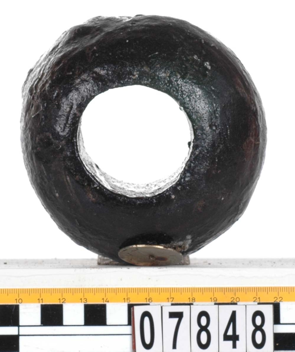 Rackklot. Runt svarvat klot med ett borrat genomgående hål. Eroderat. Asymetrisk form.