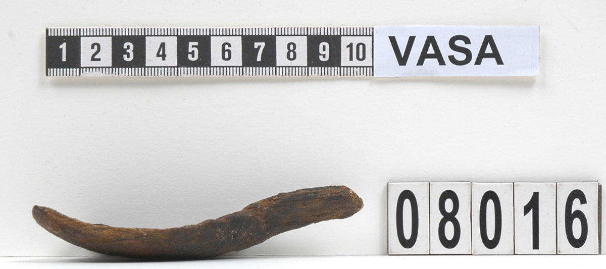 Del av en träsked.
Skedbladet är brutet upptill samt längs med ena långsidan. Skaftet är även brutet ett stycke nedanför skedbladet. På skeddelen syns en rödbrun färg som eventuellt kan vara spår efter bemålning.
Skeddelen är mycket sliten.