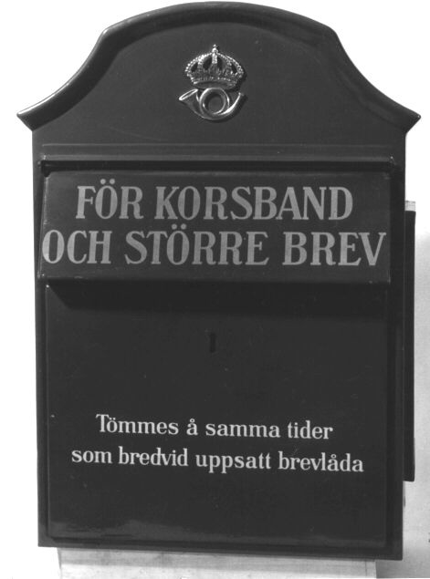 Brevlåda i blå färg med välvt tak, fronttömning och
brevinkast på fronten. På brevinkastets klaff text i versaler: FÖR
KORSBAND OCH STÖRRE BREV. På tömningsluckan text: Tömmes å samma
tider som bredvid uppsatt brevlåda. På lådans övre del i fronten ett
postemblem modell 1912. På ena gaveln en anslagsram för tömningstider.