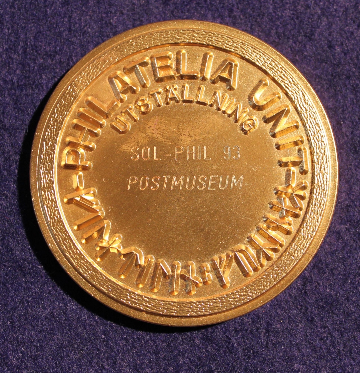 Medalj i förgyllt silver mestadels, rund. Vermeil - medaljen tilldelad Postmuseum för deltagande i frimärksutställning Sol-phil 93i Solna 3 september - 5 september 1993. Åtsidans kant där text enligt MRK står är inte förgylld. Motivet i centrum visar en hornblåsande viking, runor, en duva och trädgrenar. Konstnärssignatur: "SOE" nederst (Svenolov Ehrén). Frånsidan är helt förgylld och bärtext enligt MRK.