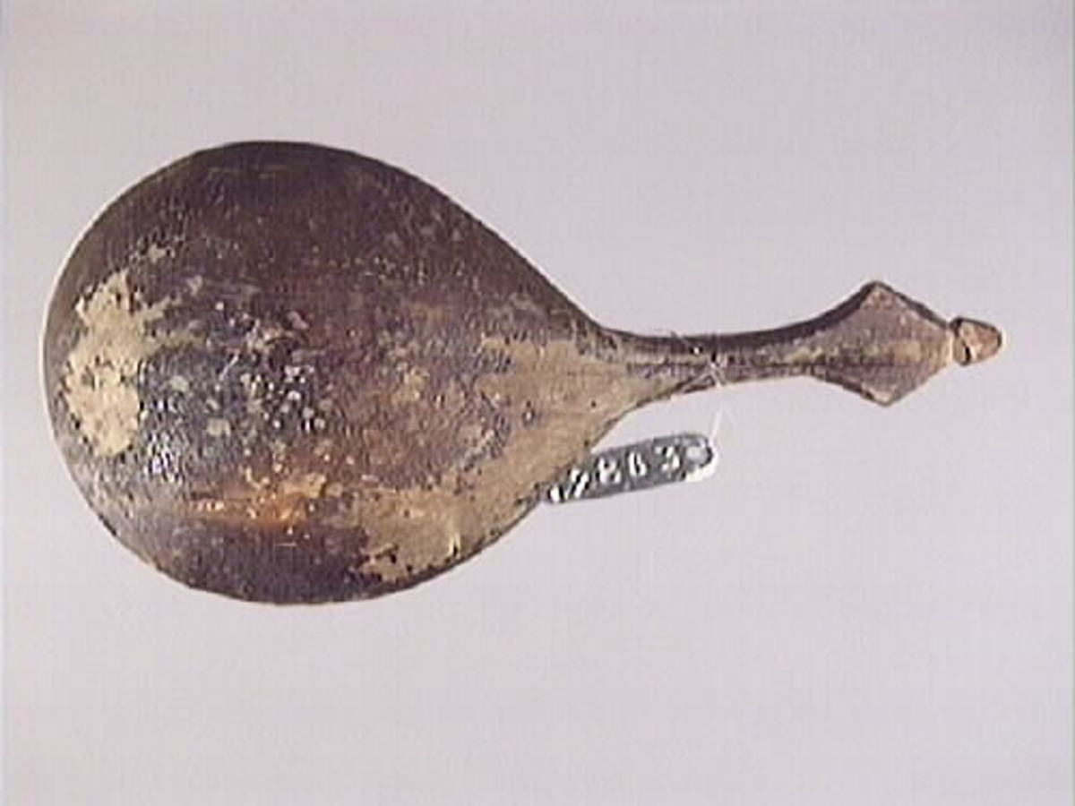 En träsked. Skeden har ett ovalt skedblad och ett kort skaft. Skaftets ände är rombformat samt försett med en liten knopp. På skedbladet syns en inristad dekor.

Skeden är välbevarad och har synliga färgspår.

För mer information se Dokumentationsblankett under Referenser – Länkade filer.