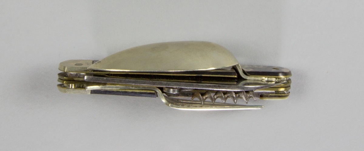 Bestick, fällkniv med handtag av horn och knivblad av stål, sked och gaffel av försilvrad metall, samt dessutom korkskruv och handskknäppare. Signerad: '59 Sauvagnat'.