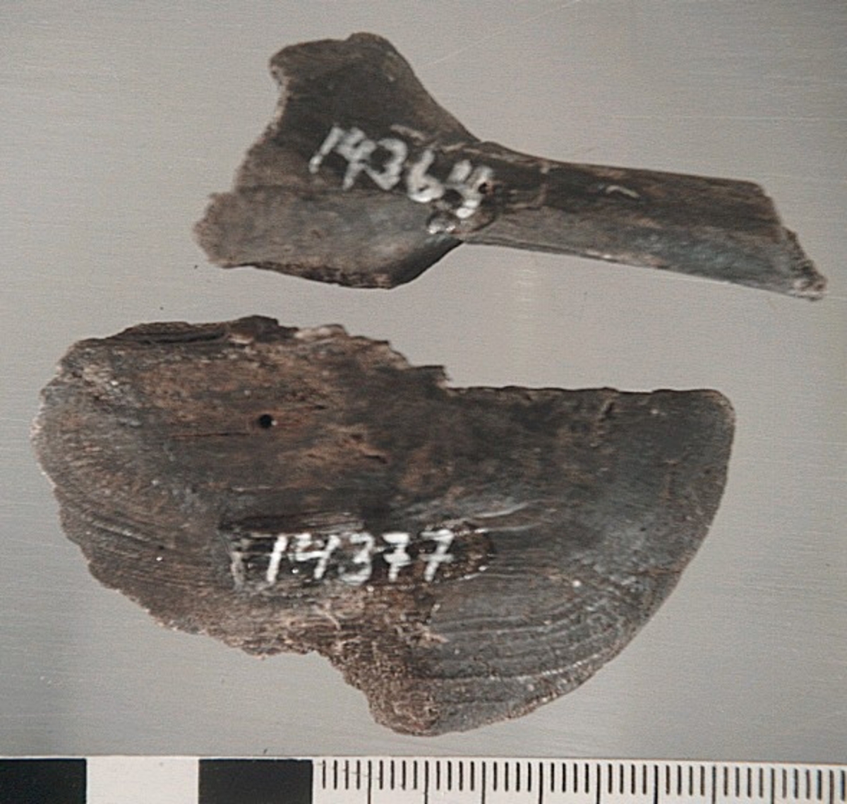 Del av en träsked. Delen utgör större delen av skedskaftet samt mindre parti av skedbladet. Skaftet är rakt och relativt smalt.

Skeddelen är bruten vid skaftänden samt upptill, vid skedbladets nedre del.

För mer information se Dokumentationsblankett under Referenser – Länkade filer.