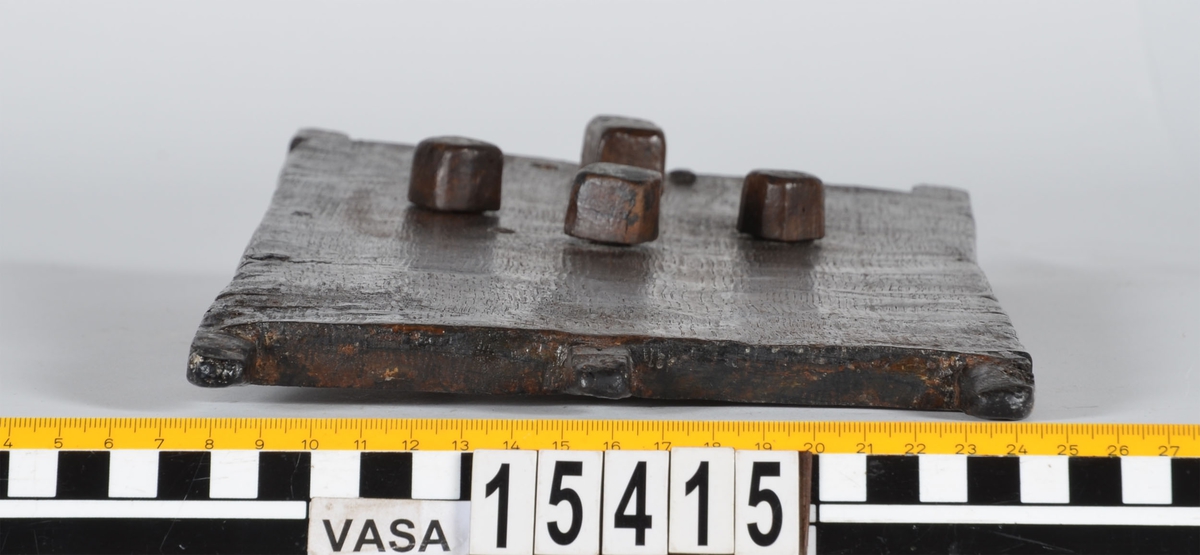 Rektangulärt träskrin med kombinationslås.



På lockets undersida sitter ett kombinationslås av trä. Låset består av en tretungad, gaffelliknande låsarm och tre låshjul. Låshjulen är försedda med var sitt inhak i vilka låsarmen låses fast. På lockets ovansida syns fyra, fyrkantiga pluggar till vilka låsarmen och låshjulen sitter fästade med trästift. Med hjälp av pluggarna regleras låshjulen och låsarmen. På vardera sida om låsarmen sitter ett mindre hål.



Lockets kortsidor är försedda med två respektive tre utstickande tappar. De två yttersta tapparna omsluter gaveln när locket är på. Den ena kortsidans mitttapp utgör låsregel. Skrinets gavlar är snedskurna upptill och har urtag på sidorna för inpassning av lockets tappar. Upptill på den ena gaveln finns ett fyrkantigt hål för låsarmen. Skrinets långsidor är falsade mot gavlarna och sitter fästade med tre trädymlingar vid varje gavelkant. På skrinets undersida finns ett hål med plugg samt tre bomärken.



Träskrinet är intakt och i gott skick, endast låsarmens trästift är rekonstruerade. Låsarmen har tidigare varit avbruten och det finns spår av lagningen i form av en tunn spricka. På skrinets ena gavel syns en spricka.



Text in English: A rectangular, undecorated box with a combination lock.



On one side of the lid is a wooden combination lock, consisting of four pegs on top that regulate a three-pronged bolt and three wheels underneath. Each wheel has a separate notch into which the bolt is inserted for locking. The bolt and wheels are each fitted to the square-shaped pegs with a small wooden pin. Situated on either side of the bolt is a small hole.



The sides are fixed by three dowels at the corners and the bevelled ends have notches on each side and a hole in the centre to fit the pegs of the lid. One end has a square-shaped notch for the bolt.



Underneath the box is a hole with a plug and three owner''s marks.

The box is intact except for the reconstructed pins. In good condition although there is a crack on one end of the box. The bolt was once broken but is now mended.