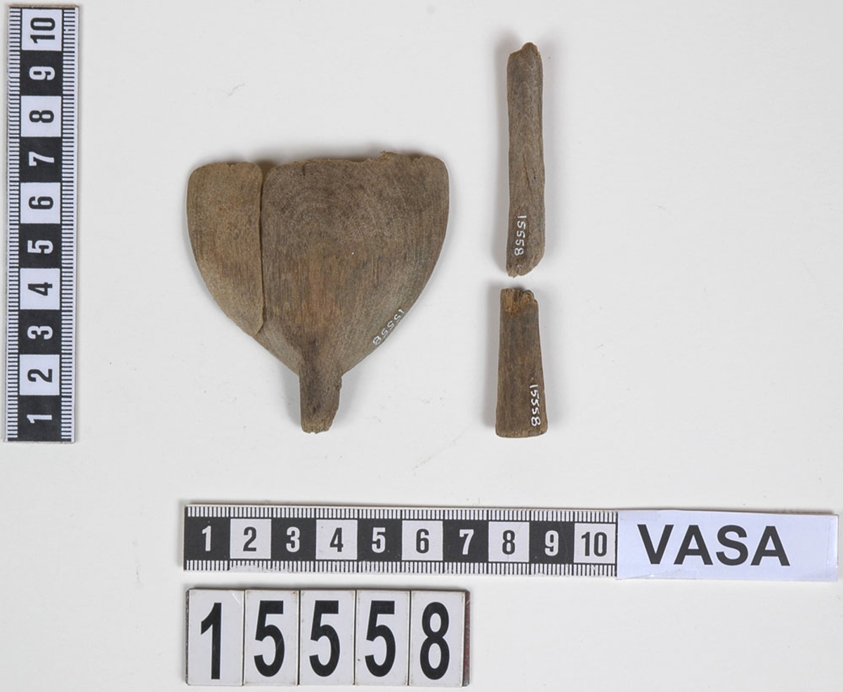 En träsked, bruten i fyra delar.

Skedskaftet är rakt och avsmalnande mot skedbladet. Skaftändens baksida är något avfasad. Skedbladet har ursprungligen troligtvis varit ovalt.

Skeden är mycket ömtålig. Skaftet är brutet på två ställen. Skedbladets övre parti saknas.

För mer information se Dokumentationsblankett under Referenser – Länkade filer.