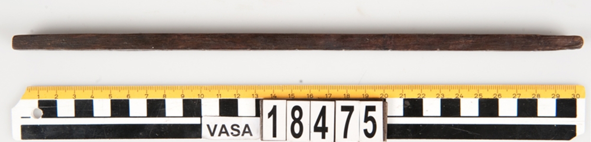 En tumstock av trä.

Tumstocken är försedd med elva inristade skåror som markerar tolv tum. På den mittersta skåran finns ett inristat kryss. Ytterligare ett kryss, dock något mindre, har ristats in vid skåran närmast mittskåran.

Tumstocken är i gott skick.

För mer information se Dokumentationsblankett under Referenser – Länkade filer.