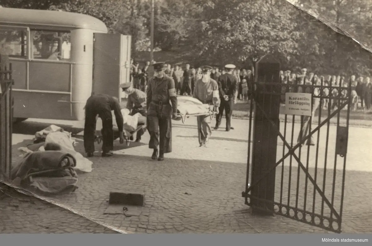 "Karantänsförläggning" på Kvarnbyskolan för överlevande från koncentrationsläger i Tyskland och Polen 1945.  
Skolan fungerade under denna sommar som beredsskapssjukhus.

Flyktingar bärs in på bår av Röda Korsets personal.