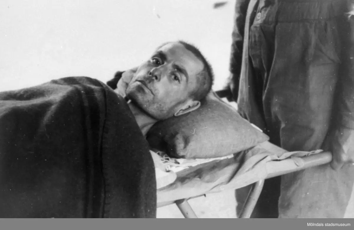 "Karantänsförläggning" på Kvarnbyskolan för överlevande från koncentrationsläger i Tyskland och Polen 1945.  
Skolan fungerade under denna sommar som beredsskapssjukhus.

En överlevande bärs in på bår av Röda Korsets personal.