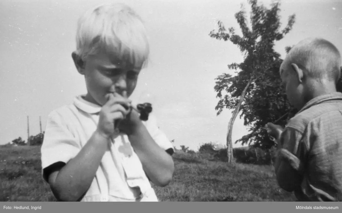 Bosgårdens barnträdgård 1938-1945. Två pojkar som blåser såpbubblor utomhus vid. Vid en intervju med förskolläraren Ingrid Hedlund berättar hon "han var så söt och hade långa ögonfransar och var ljus och vacker som en gud. Jag var med mamman, vi cyklade och lämnade bort honom på ett hem. Tragiskt, urtragiskt."