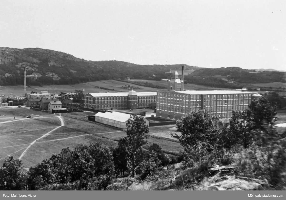 Vy över Krokslätts fabriker (Mölnlycke fabriker) med omgivningar. Claes Johansson & Co:s Väveriaktiebolags nybyggda fabrik som den såg ut omkring 1910. Spinneriet, byggnaden med tornet, stod färdigt 1907. Spinneriet har byggts till ett antal gånger under årens lopp och fick sitt nuvarande utseende 1945. Väveriet intill byggdes samtidigt med kontorsbyggnaden 1904. Bilden kommer från Mölndals Hembygdsförenings arkiv.