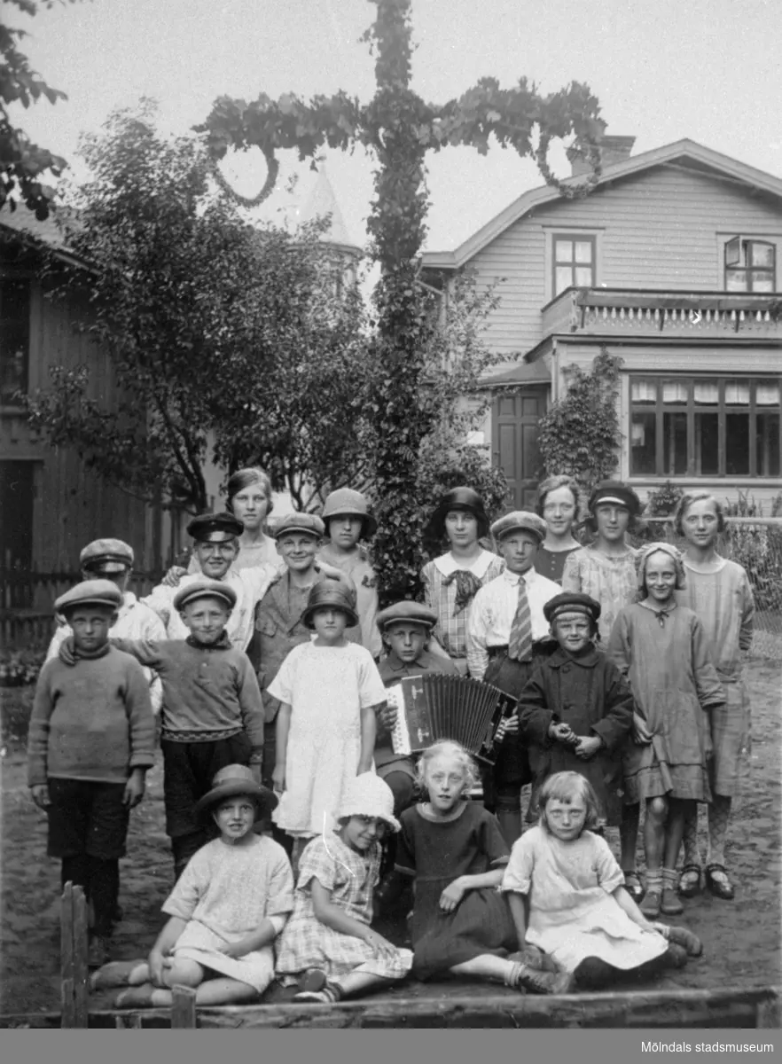 Midsommarfirande på Kvarnbygatan 23, 1920-tal.  
Första raden från vänster: Maj Hägerstrand, Lisa Malmberg, Eva Torsson och Asta Pettersson. 
Stående bakom från vänster: ?, Henry Torsson, Margot Fässberg, Bertil Fässberg (med dragsspel) och Stig Mattsson. 
Tredje raden från vänster:  ?, Tage Hägerstrand, Arne Andersson (senare Lundälv), Alf ”Ladden” och Britten Torsson. 
Bakersta raden från vänster: Astrid Andersson, Inga Andersson, Eva Johansson, Sally Torsson, Tyra Johansson och Tyra Pettersson.