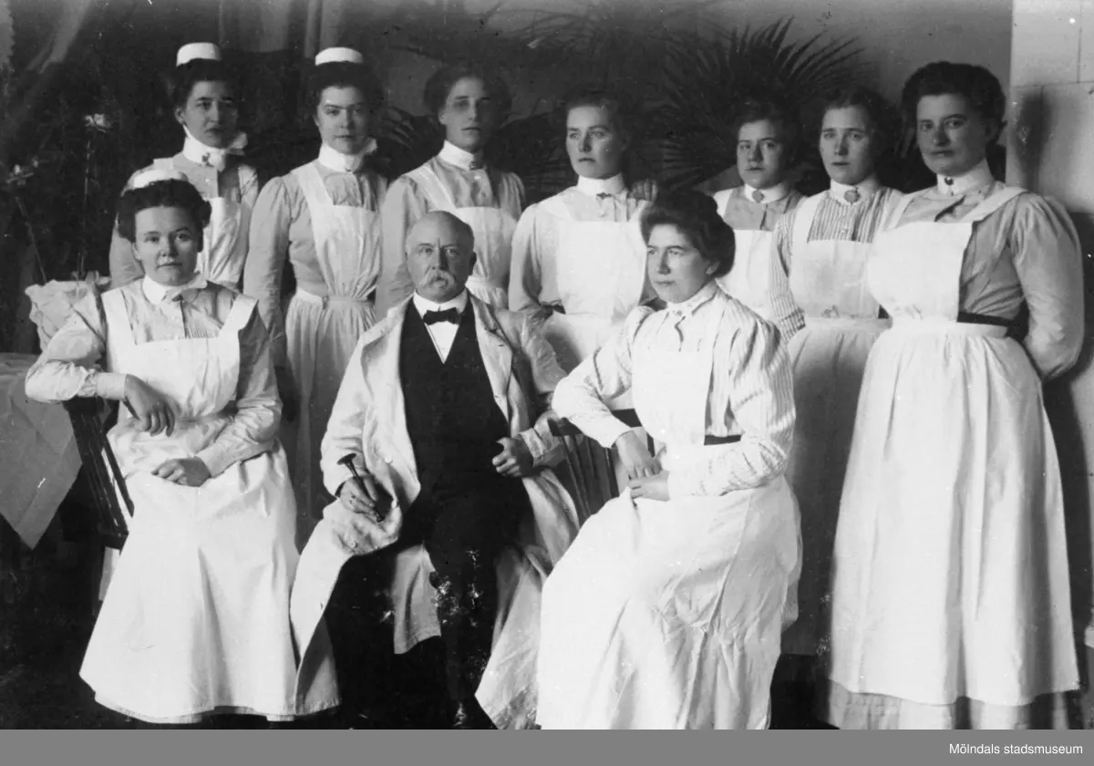 Dr Knut Belfrage sittandes omgiven av övrig personal vid sjukstugan.25-årsjubileum den 30 april 1911.