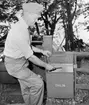 Bilåkande lantbrevbäraren Erik Johansson vid professon Bertil Ohlins brevlåda i Nykvarn. Erik Johannson arbetade på linjen Åkersberga-Singö-Björnhuvud-Åkersberga.

Foto augusti 1961.