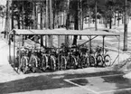 MF upptar materiel för posttjänsten som tillhandahålls av
Postverkets Centralförråd (IKC). Foto april 1970. Cykelställ, s k
cykelgarage. Med stomme av vinkeljärn och tak av galvaniserad plåt.
Dubbelsidig, med plats för 30 cyklar. Art nr 275.30.