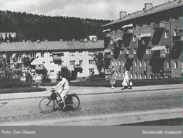 Text: "Så kom äntligen sandgropen till sin rätt. Under långa o gångna tider stadens grustag anskrämligt ful och av sådan dimension att den var svår att komma tillrätta med. Men - lösningen kom, en lycklig lösning". Flerbostadshus i kv. Hovrätten 4, sedda från Södra Tjärngatan.