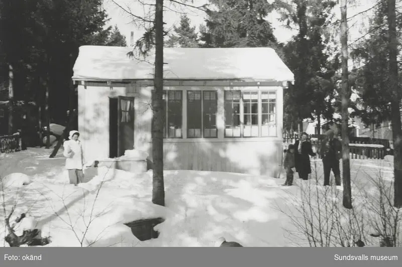 Vårvinterfoto av Oskar Söderströms ljusgula sommarstuga. Fotot taget från södra sidan av bäcken.