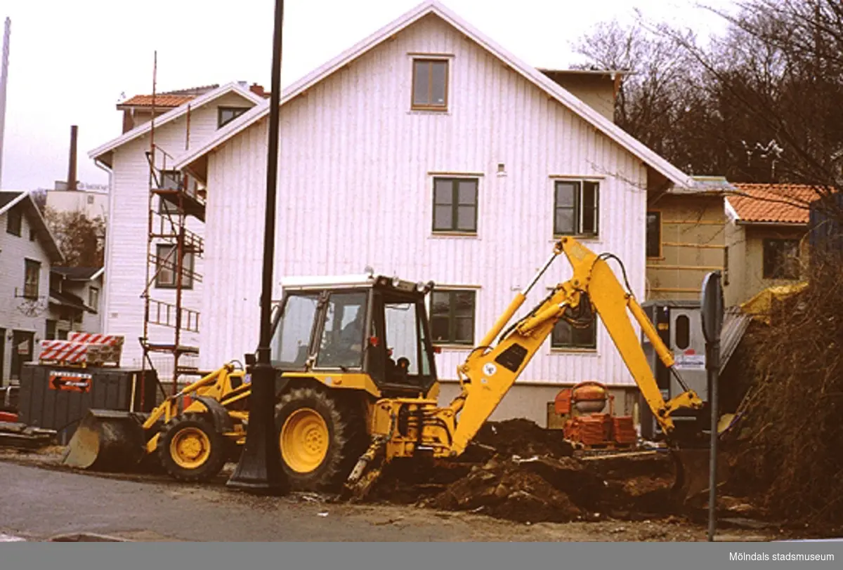 Grävmaskin vid Lyktplatsen, som håller på att iordningställas, april 1993. Bostadshuset i bakgrunden ligger på Götaforsliden 4.