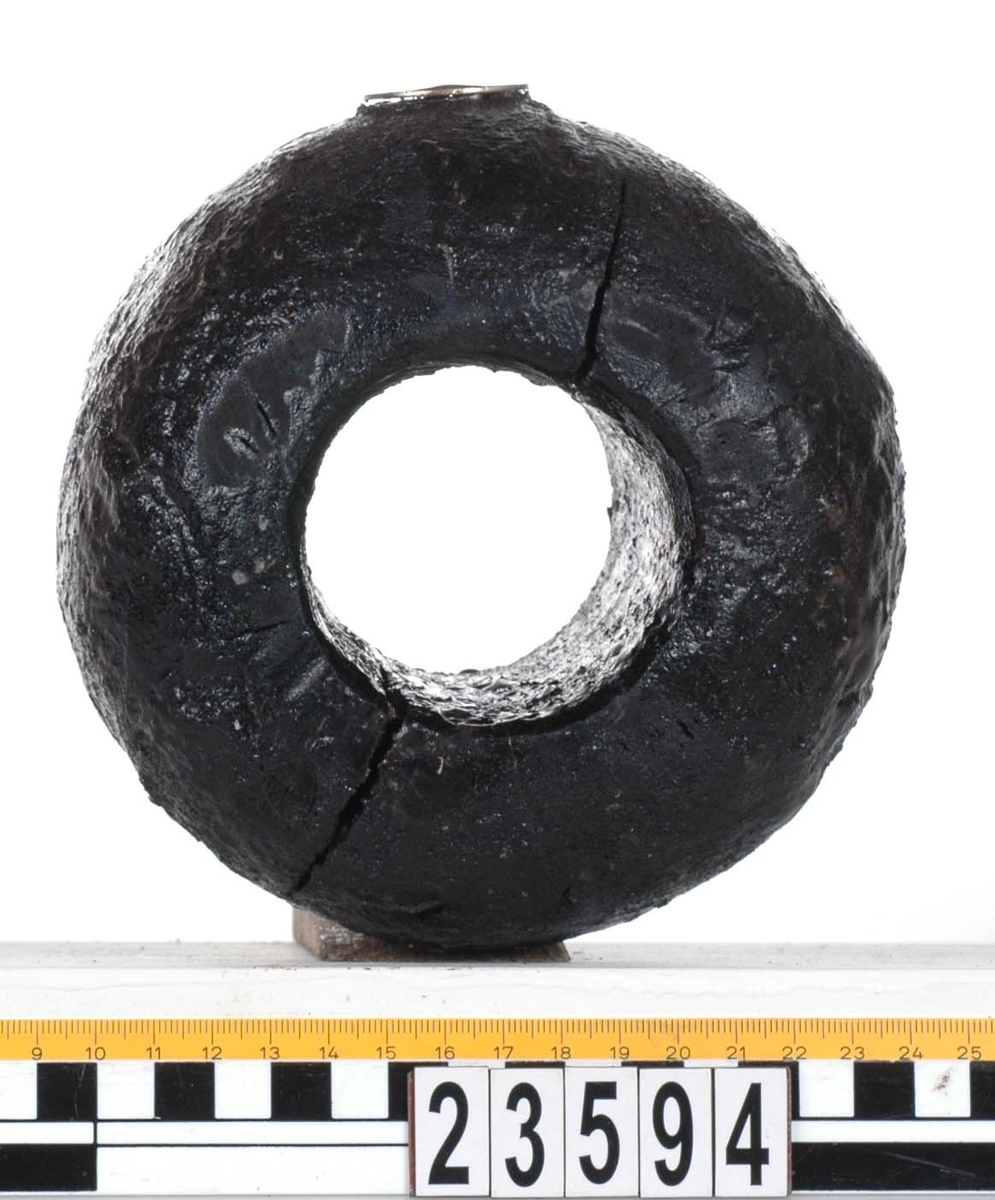 Rackklot. Runt svarvat klot med ett borrat genomgående hål. Eroderat. Tydliga sprickbildningar.