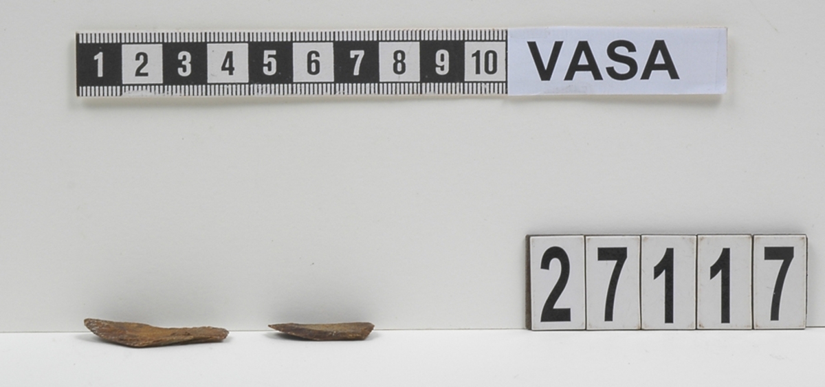 Delar av en träsked. Delarna utgör två mindre partier av skedbladet. I den ena delen syns ett litet runt hål.

Delarna är mycket slitna och fragmentariska.

För mer information se Dokumentationsblankett under Referenser – Länkade filer.