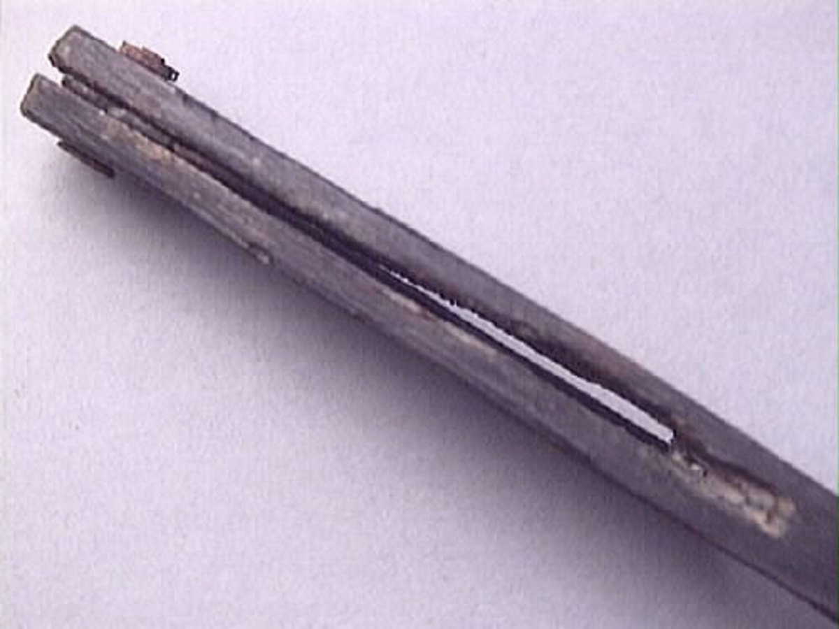 En vinkelhake, s k smygvinkel.

Skaftet är försett med sex stycken ristade skåror som markerar tum. I ena skaftänden sitter ett nytillverkat, ledat, järnblad. Bladet är fäst med en nytillverkad järnsplint. I skaftets ena ände, närmast bladet, löper en skåra eller ett spår. Spåret är mellan 68 och 80 mm djupt.

Smygvinkeln är i gott skick.

För mer information se Dokumentationsblankett under Referenser – Länkade filer.