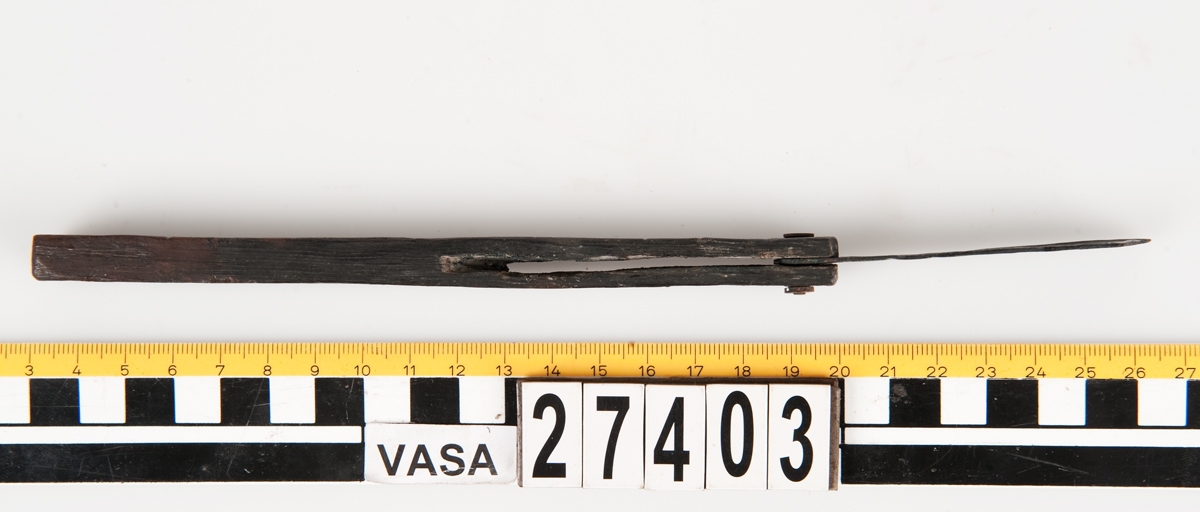 En vinkelhake, s k smygvinkel.

Skaftet är försett med sex stycken ristade skåror som markerar tum. I ena skaftänden sitter ett nytillverkat, ledat, järnblad. Bladet är fäst med en nytillverkad järnsplint. I skaftets ena ände, närmast bladet, löper en skåra eller ett spår. Spåret är mellan 68 och 80 mm djupt.

Smygvinkeln är i gott skick.

För mer information se Dokumentationsblankett under Referenser – Länkade filer.