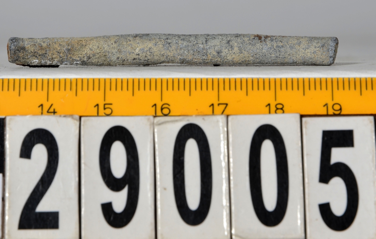 Sänket består av en vikt blybit. Sänket har tydliga märken efter det verktyg som pressat ihop sänket runt garntråden. Sänket är i gott skick.

Text in English: Lead sinker in the shape of a flat tube. The rectangular piece of lead is folded vertically in half and has visible tool marks from the folding process. The yarn is pushed through the hole. Grey mat in colour. In good condition.