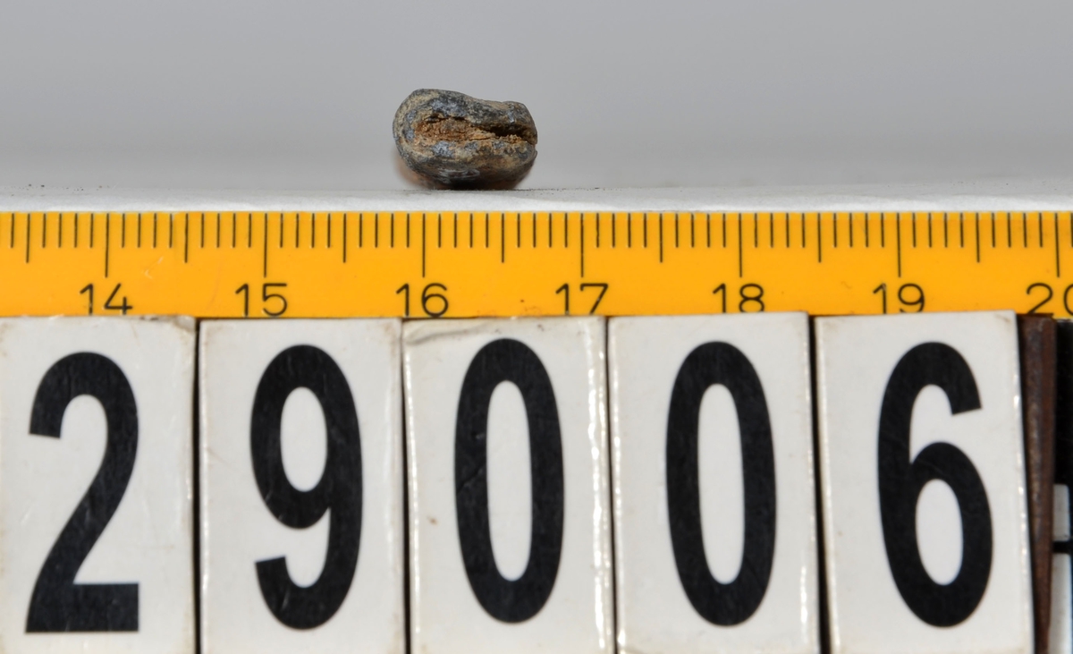 Sänket består av vikt blybit. Sänket har tydliga märken efter det verktyg som pressat ihop sänket runt garntråden. Sänket är i gott skick.

Text in English: Lead sinker in the shape of a flat tube. The rectangular piece of lead is folded vertically in half and has visible tool marks from the folding process. The yarn is pushed through the hole. Grey mat in colour. In good condition.