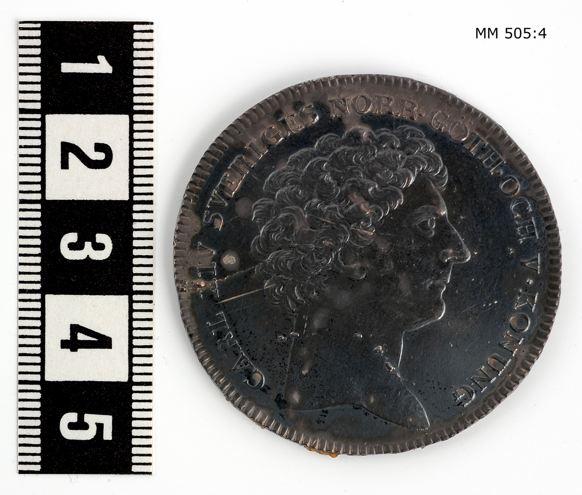 Minnespenning m.m. från slopade fartyg, inplacerade i en glastäckt låda i trä, polerad. Lådan innehåller 17 st penningar och 3 kopparplattor, de senare märkta med årtalen 1857, 1858 och 1861. Lådan innehålelr även diverse handlingar om mynten.