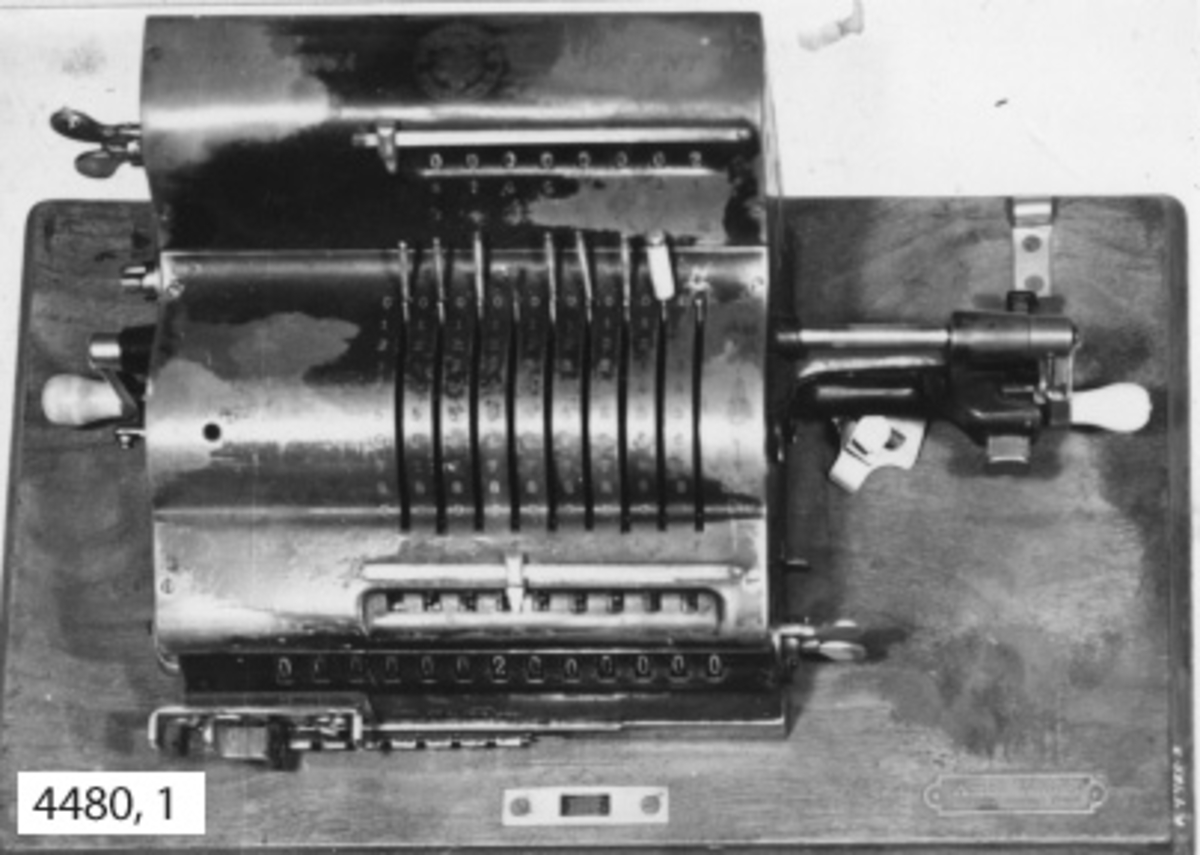 Räknemaskin av märket Brunsviga. Fabrikatet är tyskt och troligen från början av 1900-talet. Maskinen kan användas för addition, multiplikation, subtraktion och division. Den är fastsatt vid en platta av trä. Över maskinen en skyddskåpa av bleckplåt, svartlackerad och med bärhandtag av läder. Den fastlåses vid träplattan.
Märkt i gult: Brunsviga Patent samt i rund stämpel: Grimme Natalis CG. Auf Actien Brunschweig med emblem och två drakar.