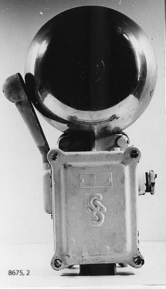Kåpan av gjutjärn, klangen av mässing. Vitmålad. Märkning: S Simens Halske 110 V 2x1000. Type T.wek 16 a-Strom.