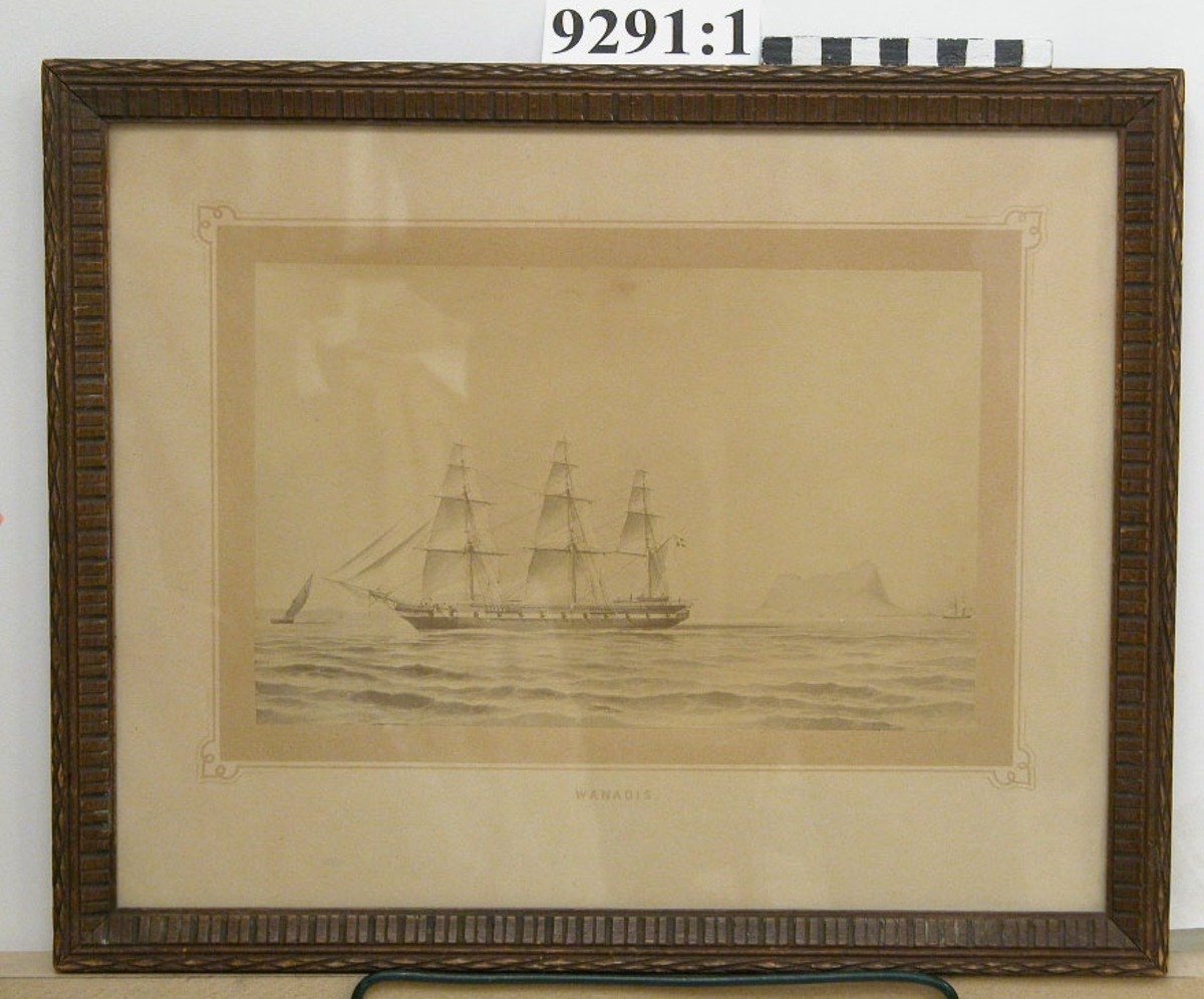 Fotografi inom glas och ram. Ramen av trä, betsad. Visar ångfregatten Vanadis under segel i Gibraltarsund under åren 1883-1885.
Märkt på kartongen : Vanadis.