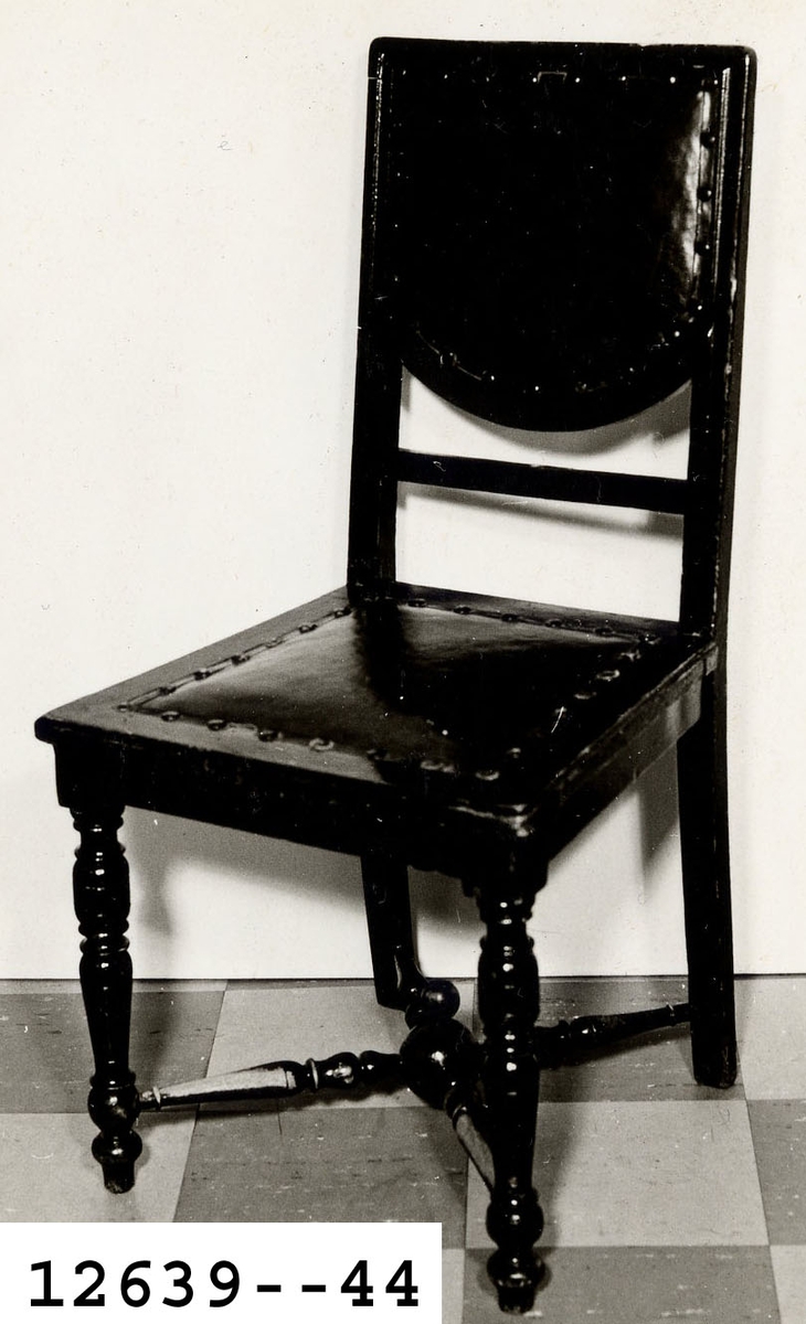 Stol av björk, betsad i mörkbrunt och fernissad. Bakbenen svängda och frambenen svarvade. Benen sammnhålls av två korslagda, svarvade slåar. Sits och rygg klädda med skinn. Märkning: "Wasa".