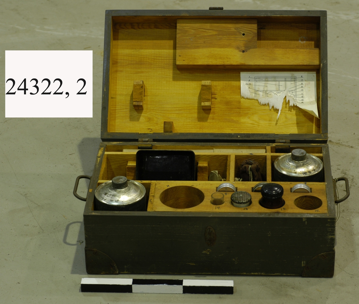 Verktygs- och reservdelslåda i trä. Försedd med flera olika fack. Innehållandes bland annat gummiringar i olika storlekar, extralampa samt mindre flaskor med natriumfosfat.