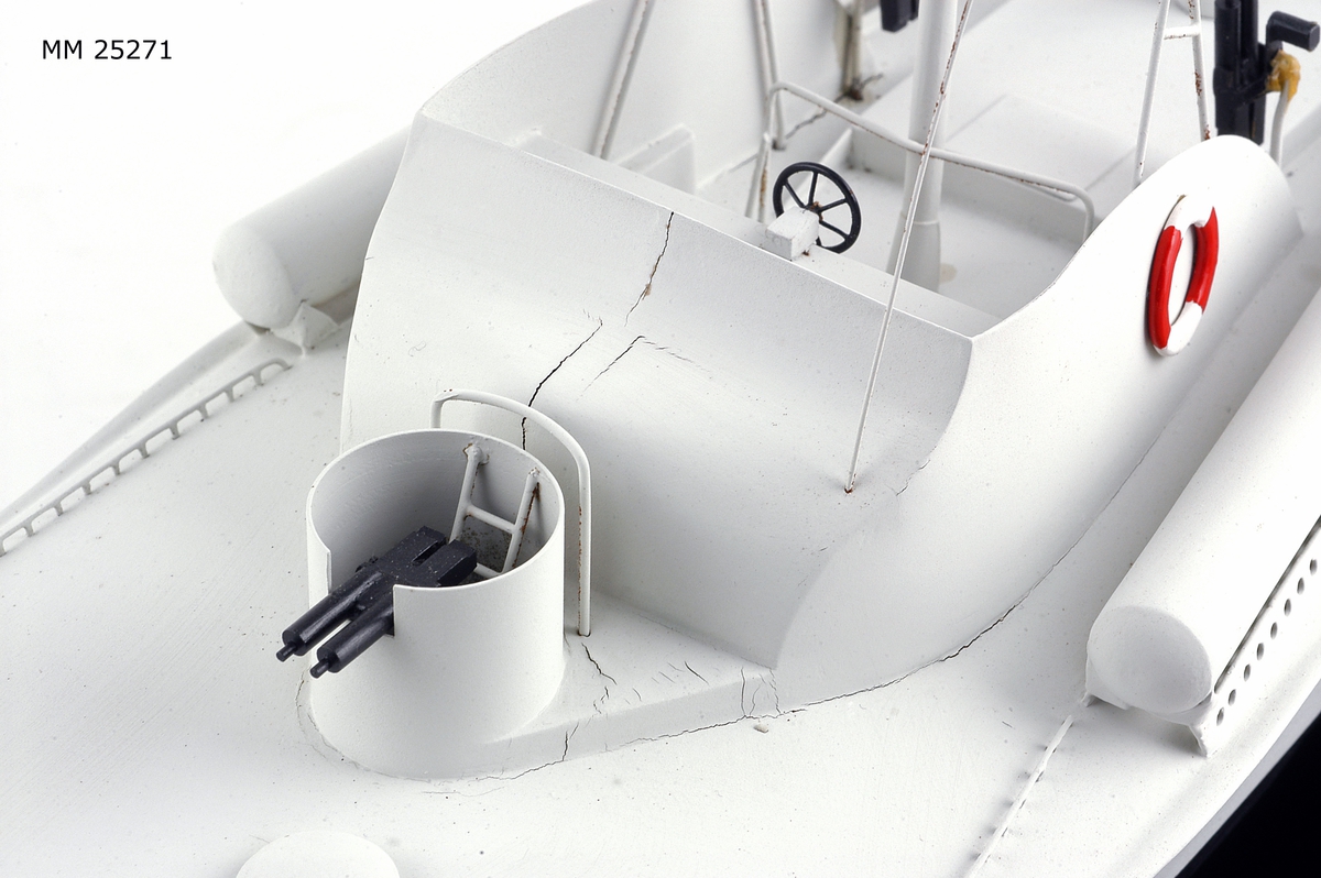 Modell av motortorpedbåten T 32. Från vattenlinjen och neråt målad i svart, från vattenlinjen och uppåt målad i ljusgrått. Märkt på stäven med skuggade bokstäver i guldfärg: "T32". På fördäck står en lysraketkastare och i en upphöjd brunnskonstruktion en dubbel KSP M/36. Mitt på fartyget en brygga med styrratt. På var sida om och bryggans sköldliknande upphöjning sitter en röd och vit frälsarkrans och något akter om dessa dubbellavettage med kulspruta M/36. Akter om bryggan sitter en luftvärnskanon i ett upphöjt brunnslavettage.
Modellen sitter på två konliknande fästen i en glasmonter med svart botten. Dimensioner avser modellen.