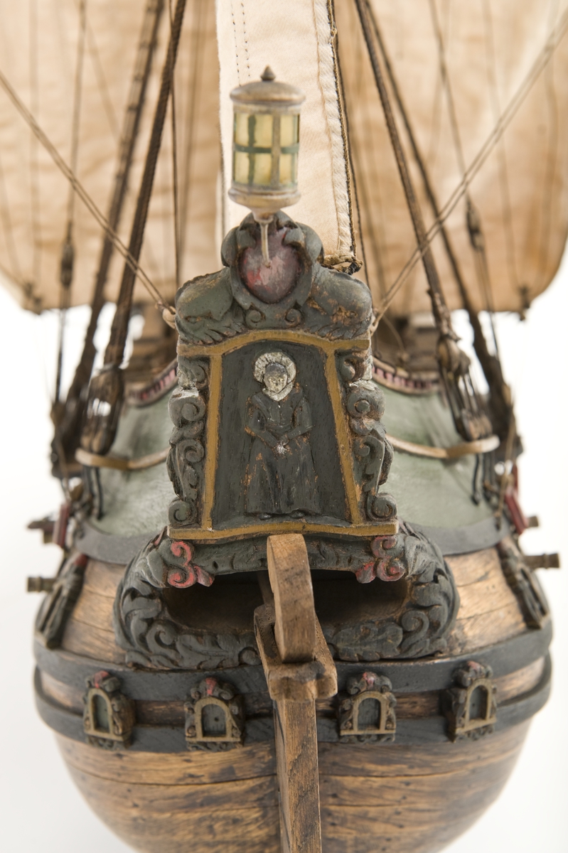 Flöjtskeppsmodell. Riggat med stående och löpande gods, segel av bomull. Bogspröt m. 2 blindor. Fock- o stormast med märs- och undersegel. Latinsegel på mesanmasten. Galjon m. lejon. 2 bogankare, båt på skrå midskeppsöver storluckan. På halvdäck 2 metallkanoner, 4 bogkanoner, samt 4 kanoner på låringen. 1 campagnelykta. Mörkbetsat skrov med 2 svarta berghult, svart bottenfärg. Akterspegel rikt ornerad med 6 fönster. Föremålets form: Helmodell