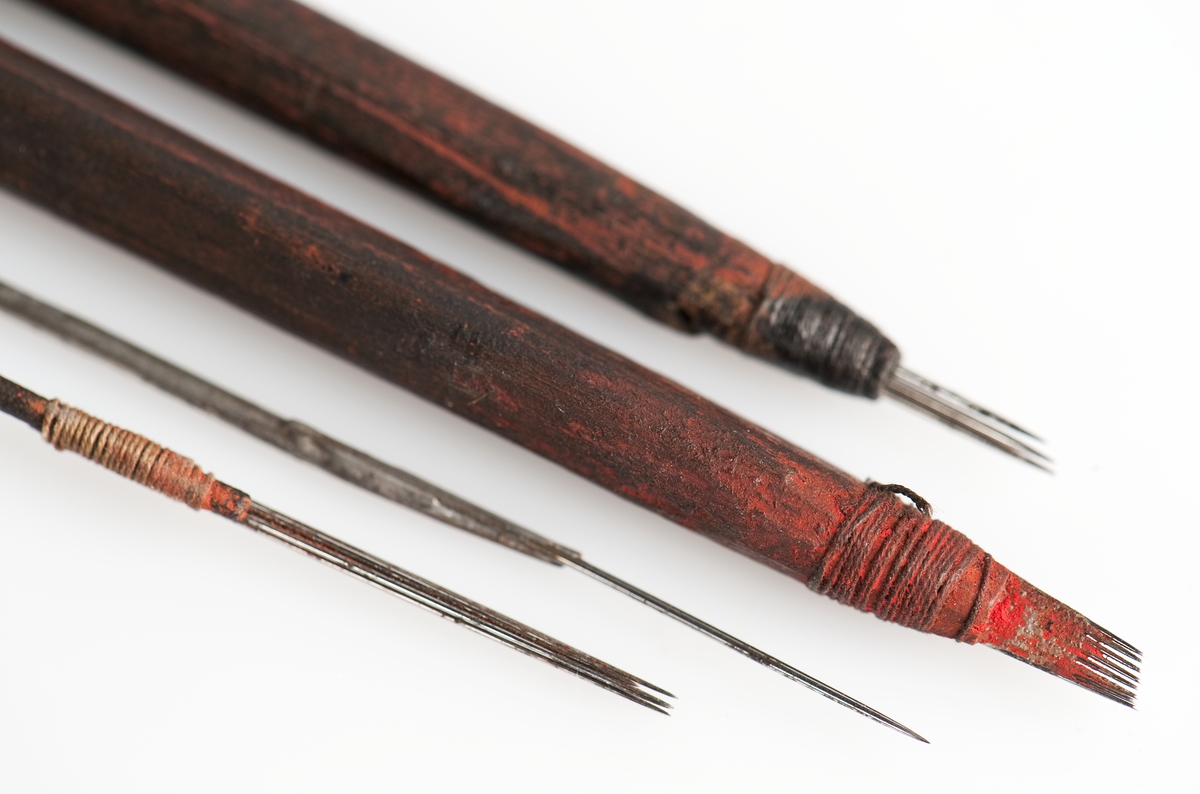 Tatueringsverktyg, skuggnål. Tre stycken synålar fästade vid ett skaft av trä. Inkom till museet 1934.