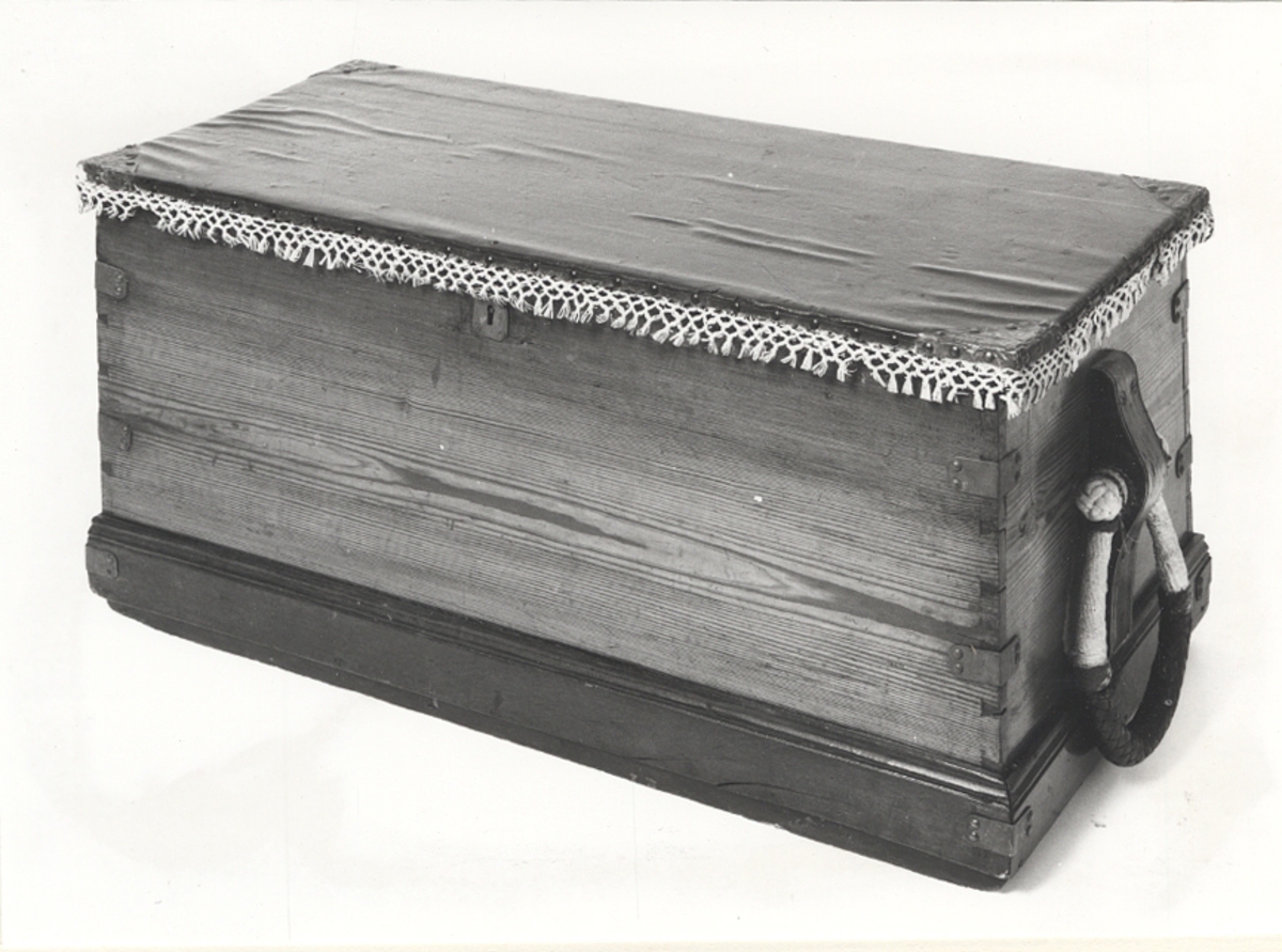 Försedd med ledika. Insidan av locket korslagda unionsflaggor påvit botten. Lockets utsida kläddmed svartmålad segelduk. Kantad med vitmålade garnbård. Handtagen sjömansarbete.Föremålets form: Rektangulär