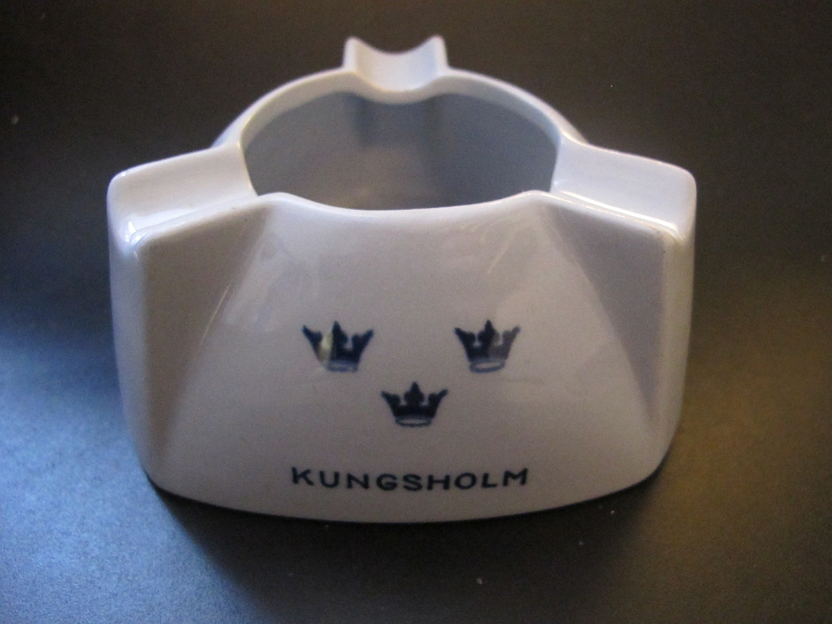 Trekantig i ljusblått porslin med höga, rundad kant avslutat med ett runt hål och tre "cigaretthållare". Text i mörkblått: KUNGSHOLM, GRIPSHOLM, DROTTNINGHOLM med SALs emblem tre kronom över vardera namnet.
Text under botten: SWEDISH AMERICAN LINE GOTHENBURG DIRECT NEW YORK & CANADAFöremålets form: Trekantig
