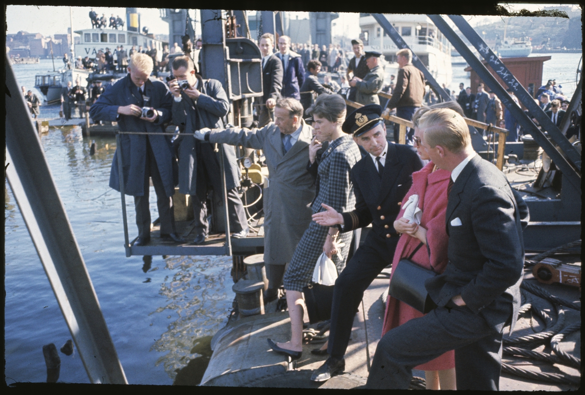 Fotografer, journalister och Kommendör Edward Clason (längst till vänster) och prinsessorna Margaretha och Birgitta ser Vasa bryta vattenytan på bärgningsdagen.