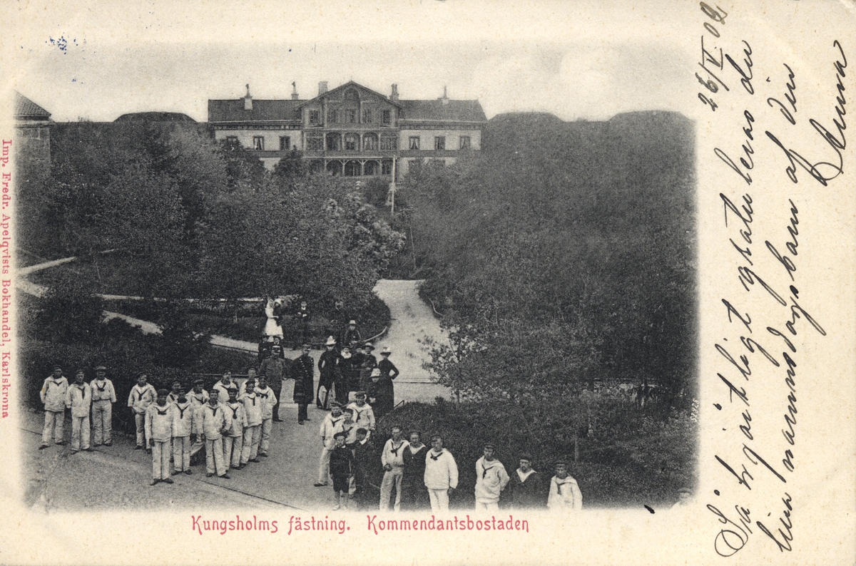 Vykort visar flottister i sommaruniform på Kungsholms fästning. I bakgrunden syns kommendatsbostaden.