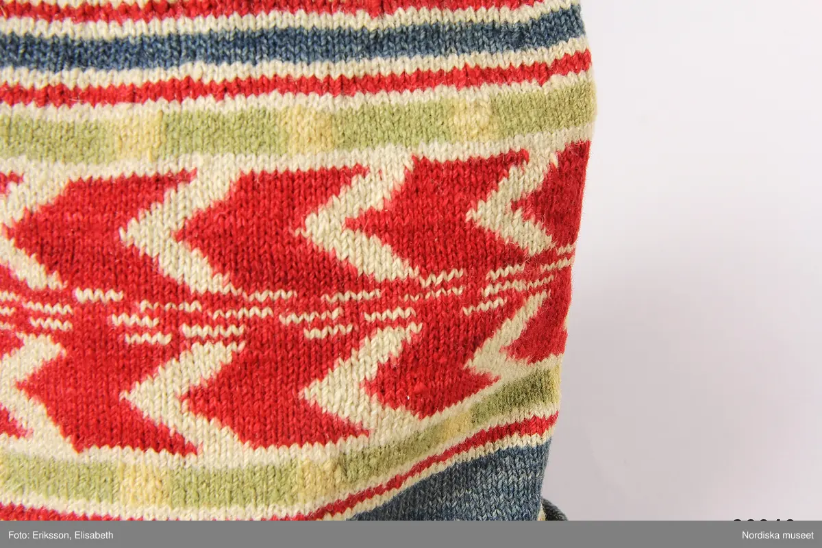 2 st röda toppluvor, A-B.
A.
B.Röd toppluva, maskinstickad i slätstickning av ullgarn, filtad, 2 stycken med nästan osynliga sidsömmar, hoptagningar i toppen. Liten röd ullgarnstofs högst upp. Nederkanten uppvikt 2 varv.

Berit Eldvik okt 2005