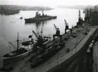 Kryssaren Tre Kronor på Stockholms ström. I förgrunden lastfartyg vid Stadsgårdskajen, år 1949.