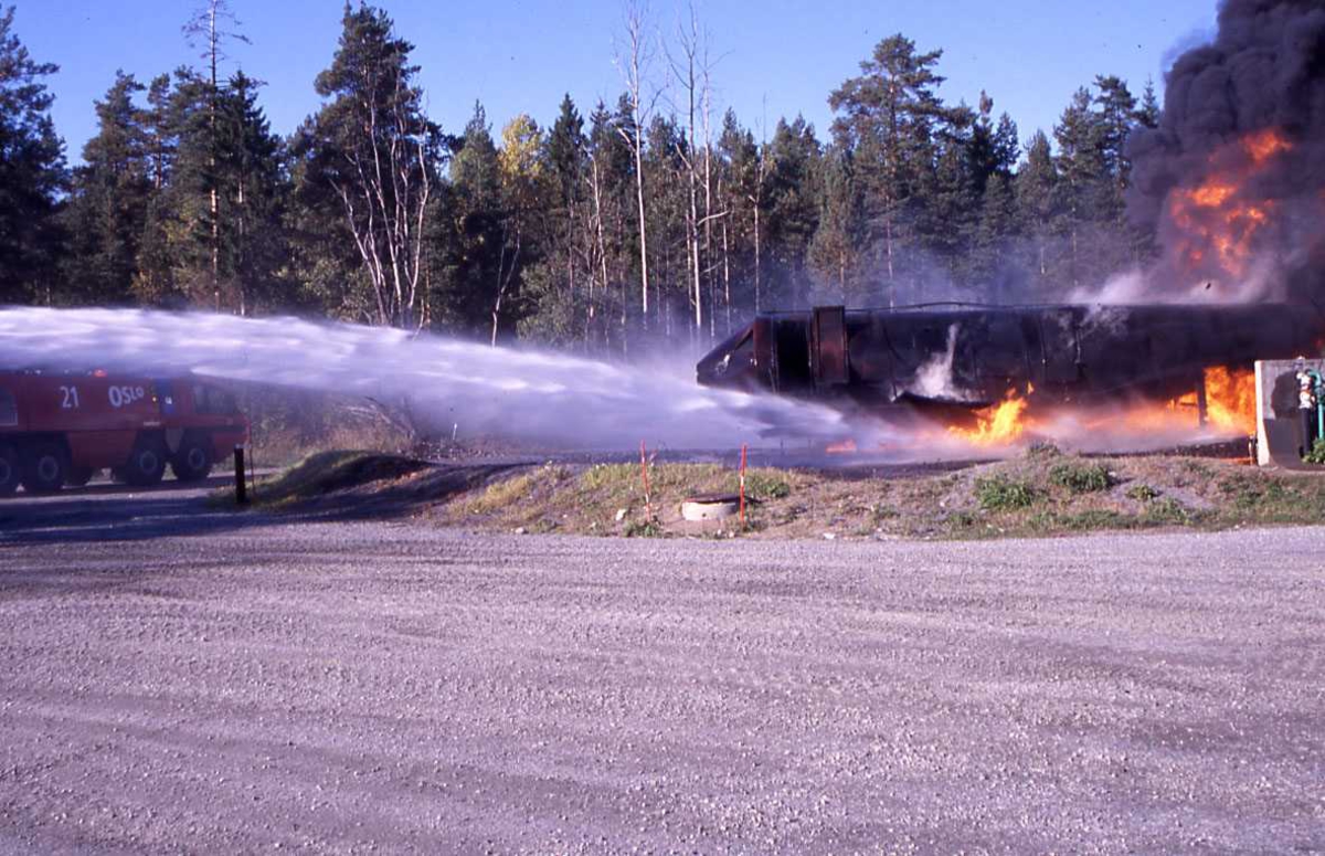 En rød brannbil spruter vann over "øvelse flyet" fra gardermoen flyplass, OSL.