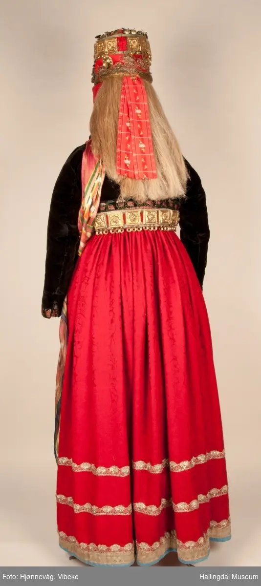 Drakten står utstilt i den faste bunadutstillingen på Hallingdal Museum, Nesbyen.  Den ble satt opp på grunnlag av et bilde fra Norsk Folkemuseum, tatt ang. av Axel Lindahl.  Tidfestet til 1877-78.  Høyde på overdel ble bestemt etter lengden på trøya.  Utelatelsen av det store bryststykket og andre forandringer ble diskutert med Ågot Noss og godkjent.  Ny dokke ble bygd opp med utgangspunkt i stakkens mål.
HFN 03387-stakk med liv.  Stakk og liv ble skilt 5.1.1999, rød ulltråd med tråklesting festet delene sammen, fjernet.  Stakk festet til liv i ny høyde med store attersting med rødt bomullsgarn.  Det ble sydd understakk i ubleket lerret med vattering av dacronvatt, for å få riktig profil.
HFN 03386 Forkle er noe for kort.
HFN ? Skjortering, sydd fast i skjorta.
HFN 00677 sølje, sydd fast i skjorta.
HFN 00533 sølje sydd fast i skjorta.
HFN ? Perleklut, sydd fast i skjorta.
HFN 00560 Angus Dei, påsatt ny silkesnor.
HFN 06695 Silketørkle, blått, festet i forklesnora
HFN 03499 Silketørkle festet i forklesnora
HFN 06694 Silketørkle, rødt rundt halsen
HFN 03603 Brudelue
HFN 03137 Stølebelte, påsatt bendelbånd, disse ligger over skuldrene for å holde beltet oppe.
HFN 03318 Linskjorte.  Vasket: desember 2000
HFN 01815 trøye i svart speilfløyel.