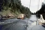 Motorbåt och folkbåten KARP på väg genom Väddö kanal.